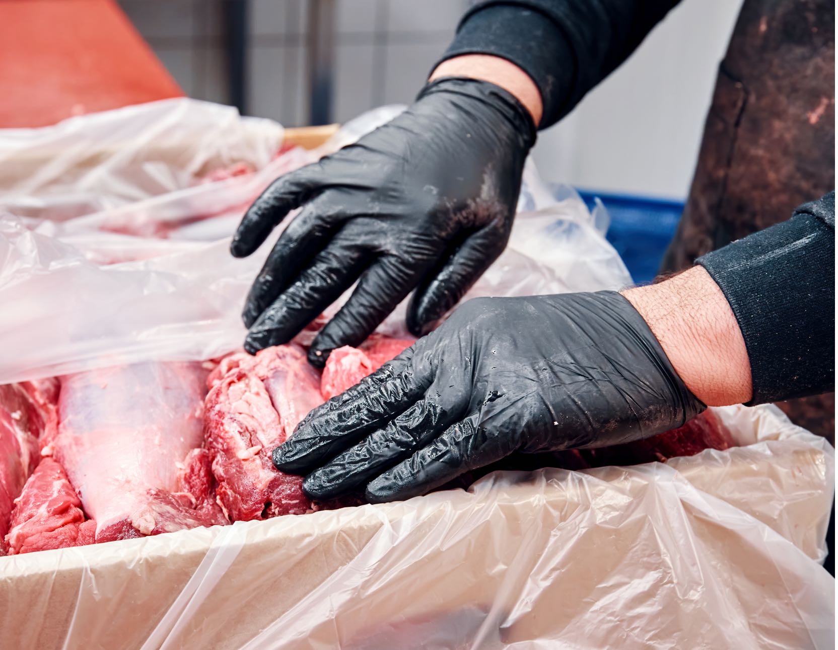 A person packing meat into a container.